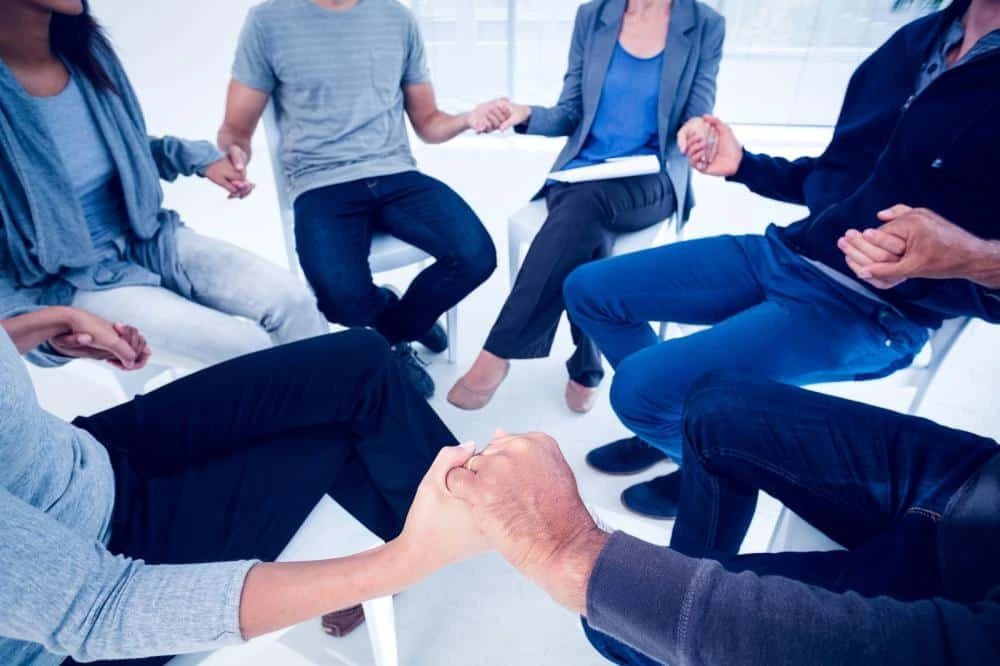 group therapy with people holding hands in a circle